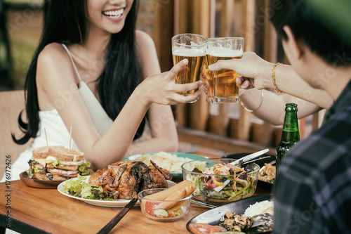 Beautiful Asian women are holding a glass of beer and cheers with her friends. She have smiling face and laughter.