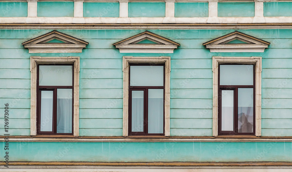 Three windows in a row on facade of urban apartment building front view, St. Petersburg, Russia