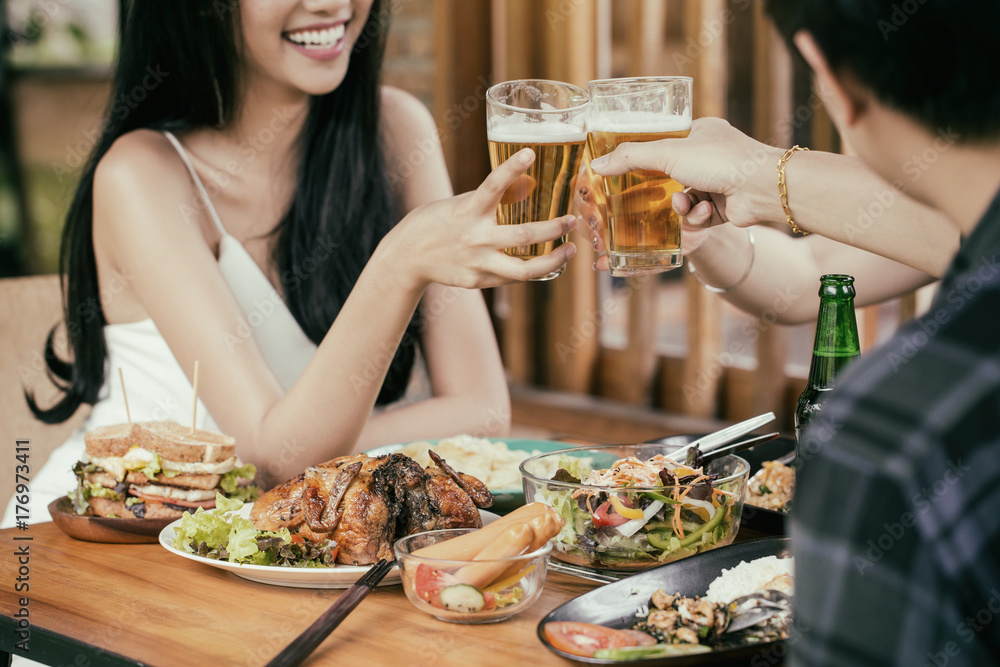 Beautiful Asian women are holding a glass of beer and cheers with her friends. She have smiling face and laughter. Beautiful Asian women are holding a glass of beer and cheers with her friends. She have smiling face and laughter.