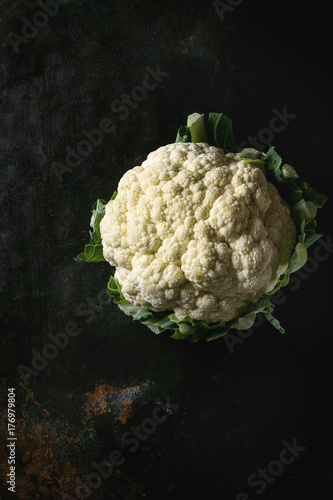 White fresh raw organic cauliflower over dark texture background. Top view with space. Healthy eating concept