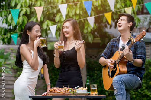 Canvas Print Asian young man are playing guitar with girls at the outdoor party