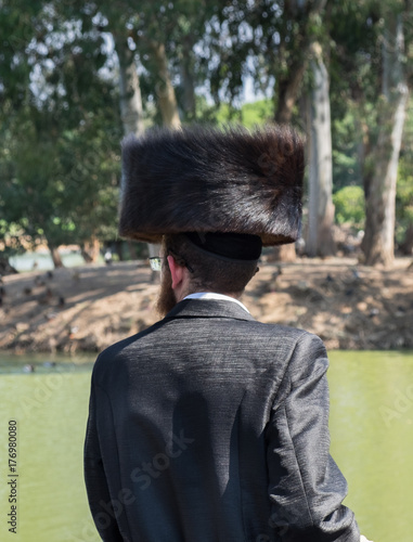 Undefined orthodox jewish man looking on pond in municipal park. Israel photo