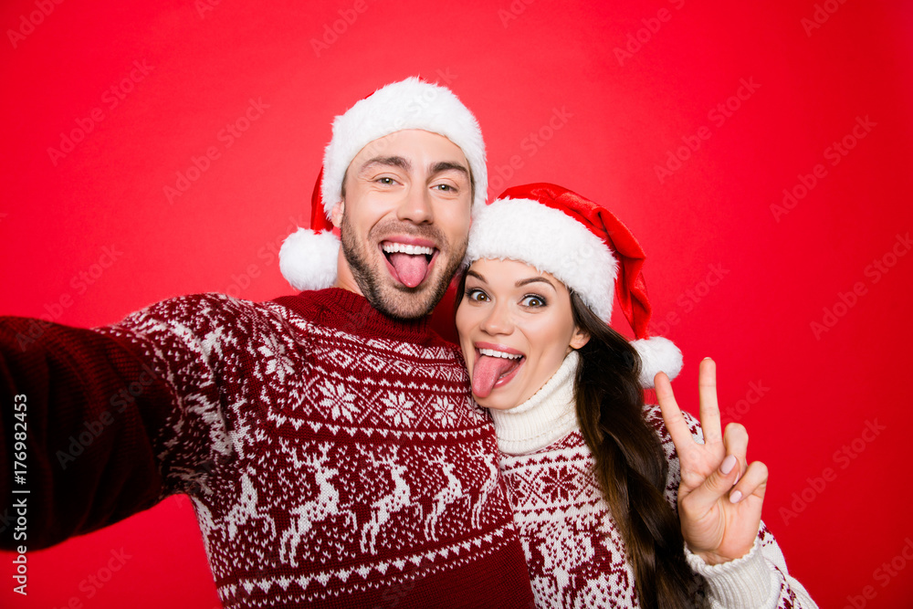 Funky, happiness, party! Cool funny playful partners bonding hug embrace in knitted traditional clothing, head wear, taking selfie with sticking tongues, making comic grimaces, fooling around Funky, happiness, party! Cool funny playful partners bonding hug embrace in knitted traditional clothing, head wear, taking selfie with sticking tongues, making comic grimaces, fooling around