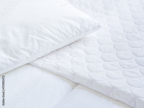 Closeup of white pillow cover sheet and topper bed.