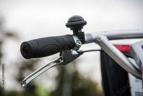 Bicycle handlebar, brake lever and bel close-up over blurred avenue