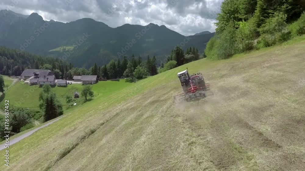 The machinery is moving very fast when someone is preparing hay. Aerial shot. It's a nice day up in the mountains. The machinery is moving very fast when someone is preparing hay. Aerial shot. It's a nice day up in the mountains.