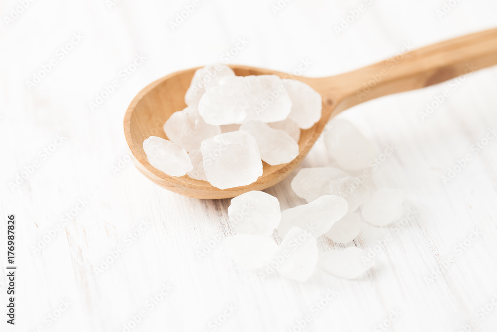 Lump sugar in wooden spoon on white wooden table Lump sugar in wooden spoon on white wooden table