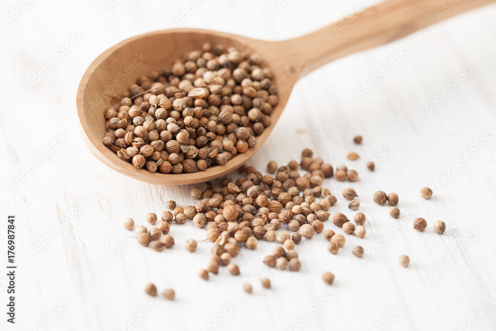 Coriander in a wooden spoon on white wooden table Coriander in a wooden spoon on white wooden table