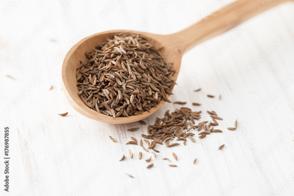 Black cumin in wooden spoon on white wooden table Black cumin in wooden spoon on white wooden table
