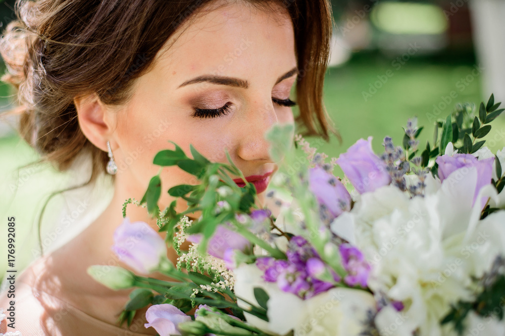 Dreamy bride holds violet bouquet before her face Dreamy bride holds violet bouquet before her face