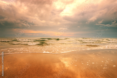 Fototapeta Naklejka Na Ścianę i Meble -  dramatic sunset on the beach and wave bubble on sand