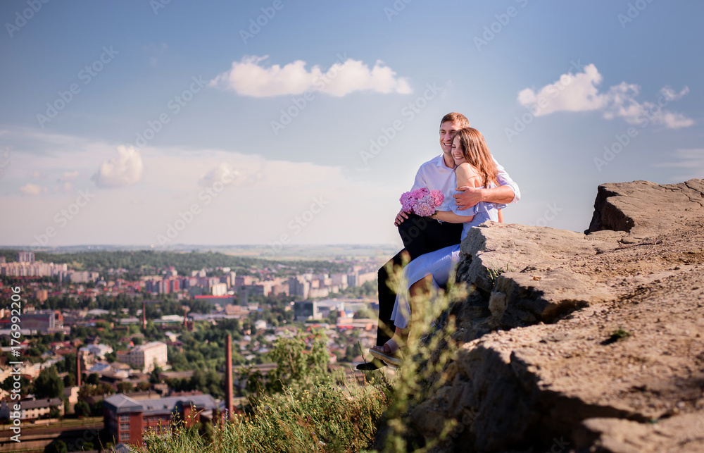 Charming couple sits with glasses of champagne on the rock Charming couple sits with glasses of champagne on the rock