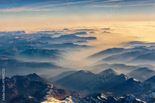 Top view from airplane  Beautiful view on the mountains from the top through the clouds.