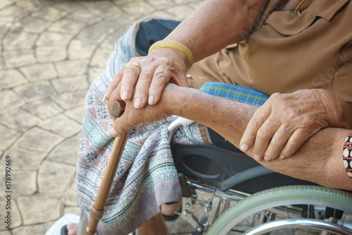 old man take care old lady sit in wheelchair and hold in hand together