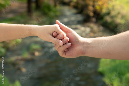 A man's hand holds a woman's hand against the background of a stream © Bogdan