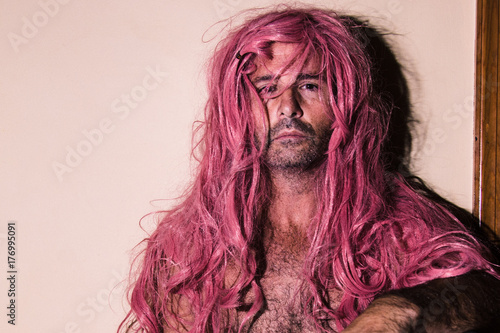 Shirtless Man with Pink Hair Sitting Against Wall