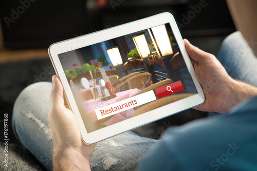 Man using tablet trying to find the perfect restaurant from review website or application. Tavern, cafe or bistro search engine and app online. Rating social media on internet.