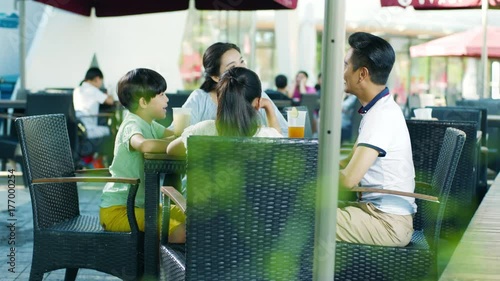 asian family drinking & talking at outdoor seating enjoying happy family time in slow motion