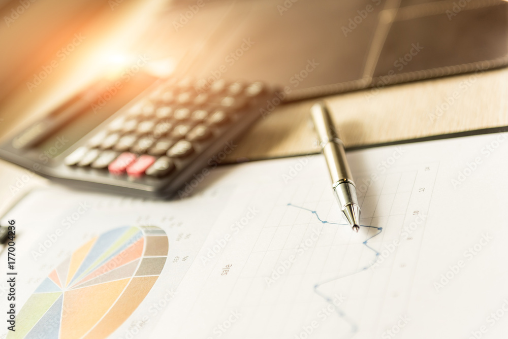 ballpoint pen on the graphic document and calculator, finance business working online concept. ballpoint pen on the graphic document and calculator, finance business working online concept.