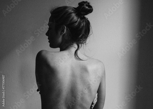 young woman with bare back towards camera intimate studio black and white photo