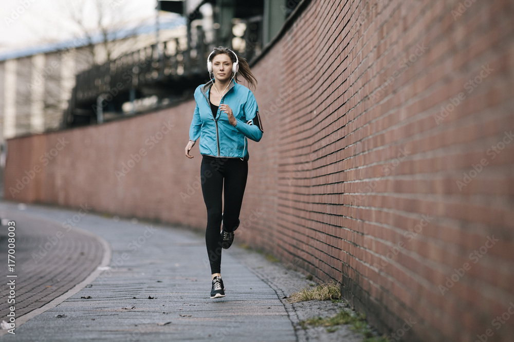 Female jogger running in an urban environment Female jogger running in an urban environment