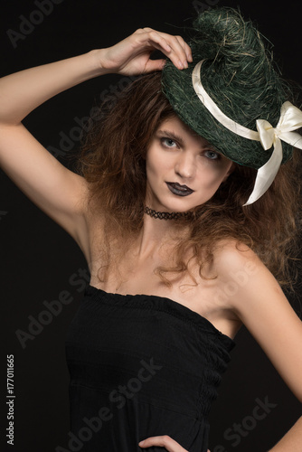 Beautiful woman witch in dress with hat on head on black background for holiday halloween