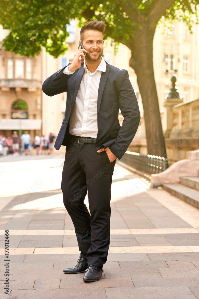 Young businessman talking on a phone on the sunny street Young businessman talking on a phone on the sunny street