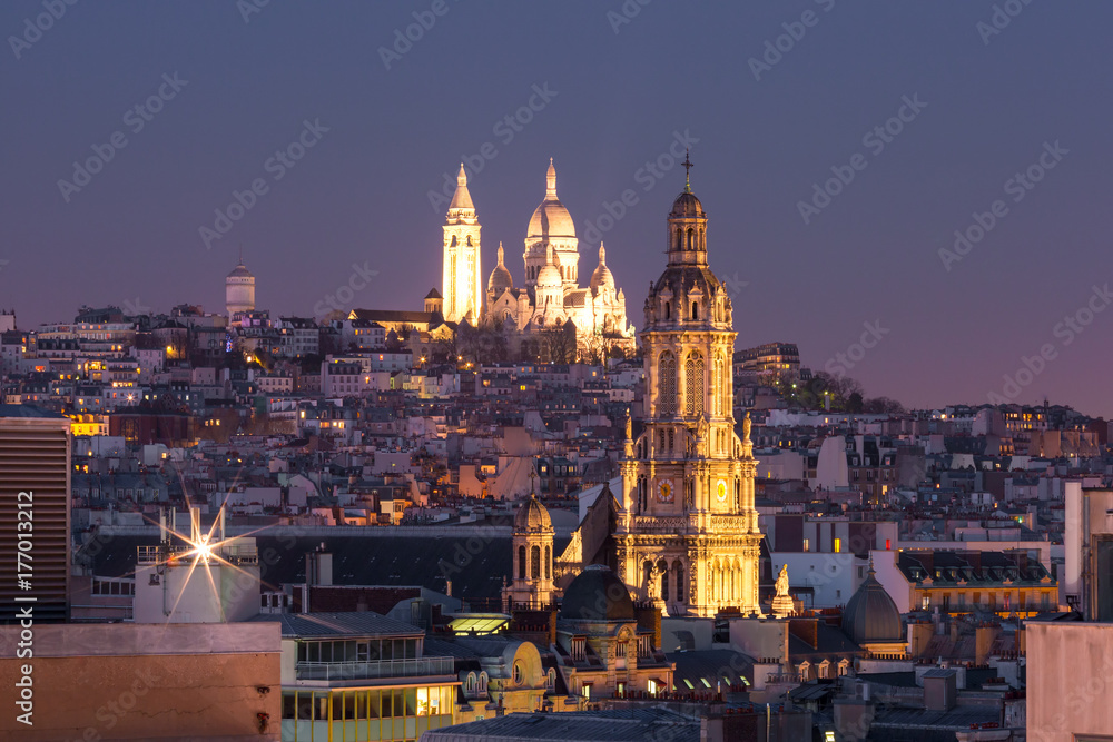 Aerial view of Sacre-Coeur Basilica or Basilica of the Sacred Heart of Jesus at the butte Montmartre and Saint Trinity church at night, Paris, France