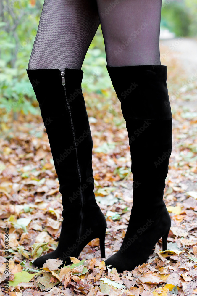 Women's legs in boots on leaves. Beautiful long female legs in black boots against a background of yellow autumn leaves. women's shoes on the autumn street Women's legs in boots on leaves. Beautiful long female legs in black boots against a background of yellow autumn leaves. women's shoes on the autumn street