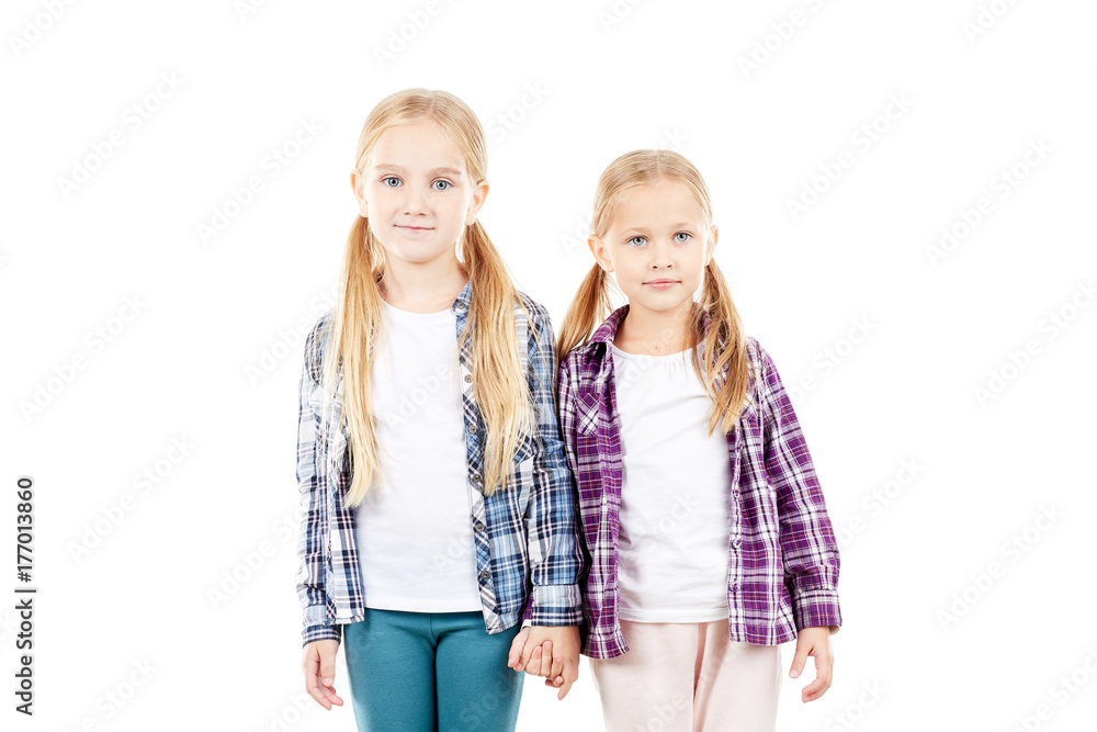 Portrait of cute little sisters in checked shirts posing on white background Portrait of cute little sisters in checked shirts posing on white background