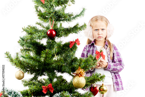 Studio portrait of little girl decorating Christmas tree