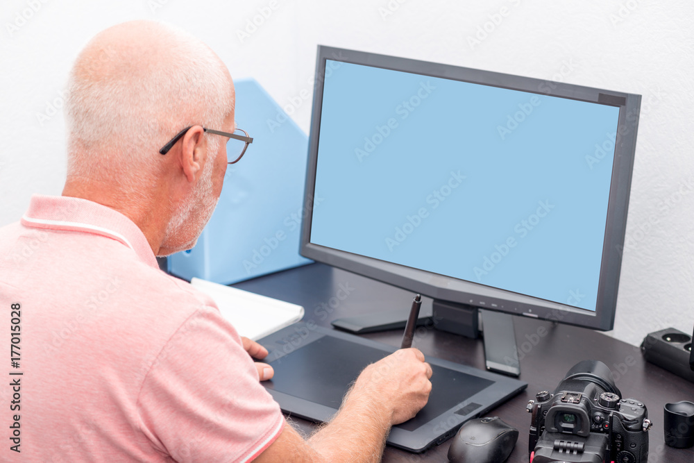 mature man working with  graphics tablet in his office