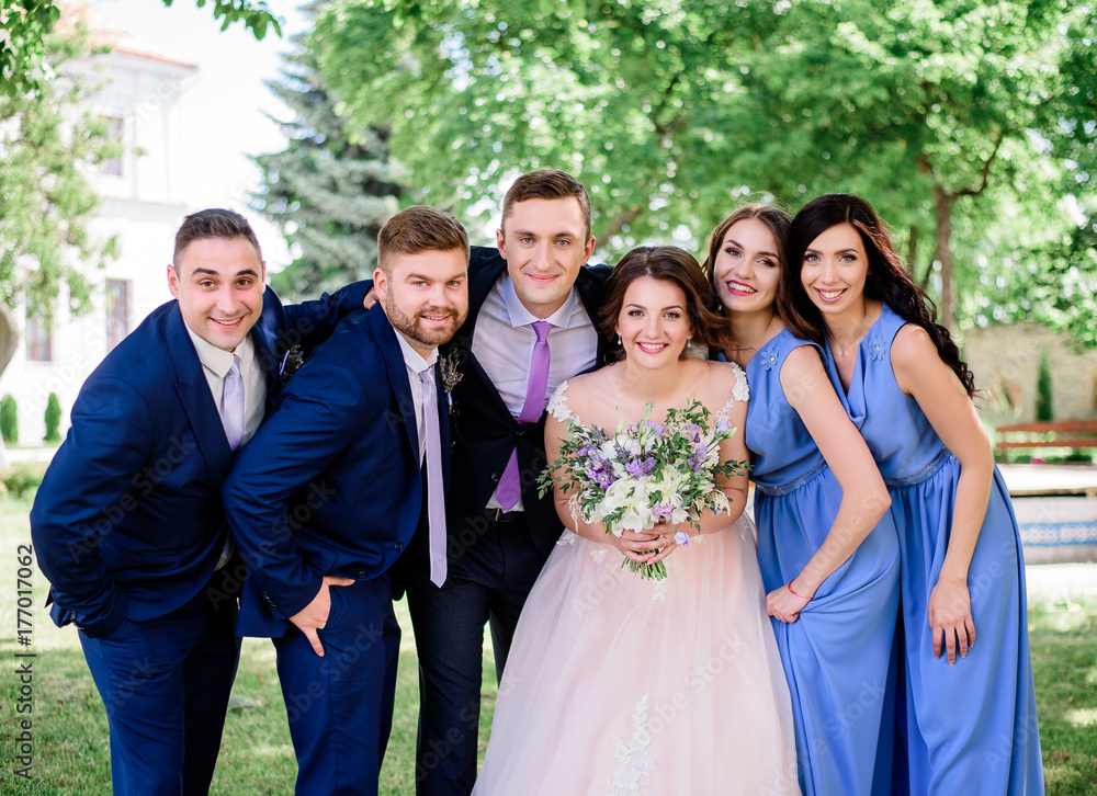 Wedding couplle, bridesmaids and groomsmen pose together in the park
