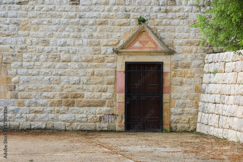Obraz premium Closed wooden door with stone frame in a church stone wall in Ain Qani, Lebanon.