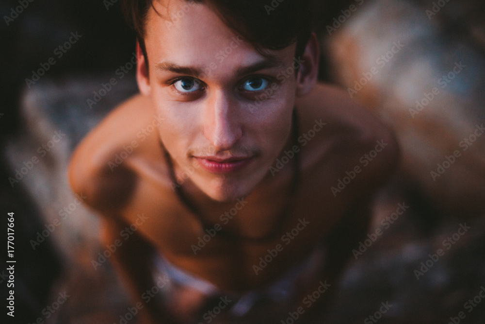 Close up shot of a young beautiful man on the rock from above Close up shot of a young beautiful man on the rock from above