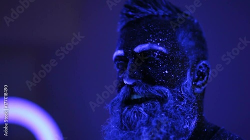 An evil man with a beard in the ultraviolet light is frighteningly screaming photo