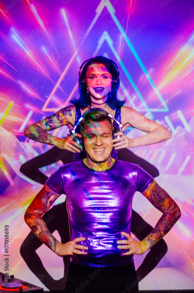 the girl with the guy in the background of the projector screen . Love couple DJs and play music . Festive disco the girl with the guy in the background of the projector screen . Love couple DJs and play music . Festive disco