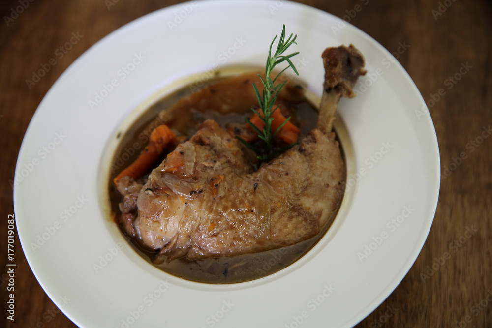 Coq au vin, chicken stewed in red wine with carrots and potatoes on wood background , France food