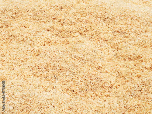 Texture of natural wood chips, the surface of a heap of fresh sawdust of a non-uniform beige color. Logging, lumber, timber and carpentry waste