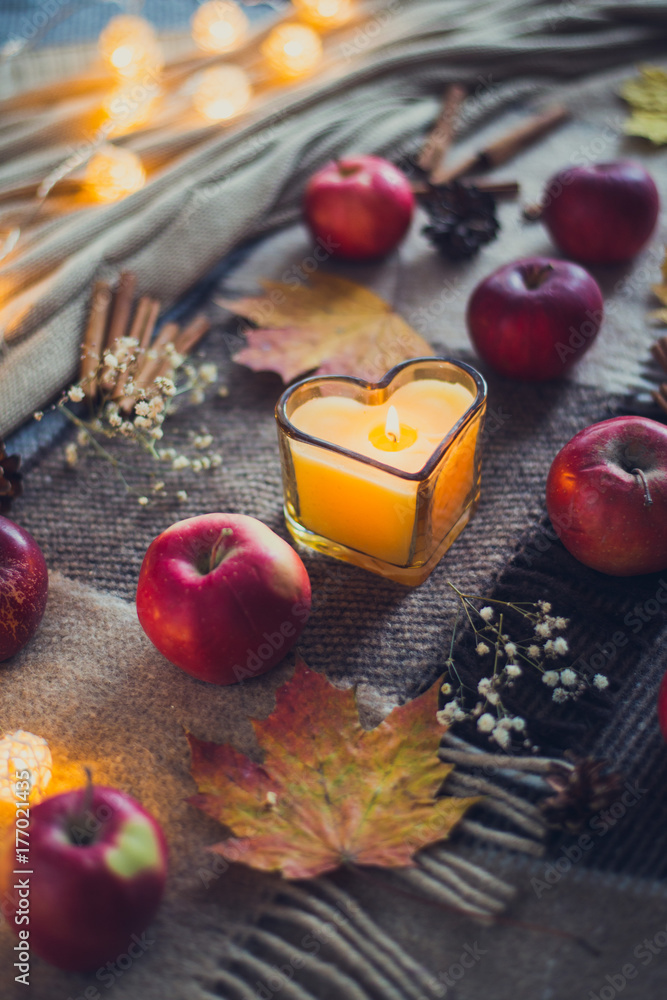 autumn composition of apples and candles, pine cones, warm blanket autumn composition of apples and candles, pine cones, warm blanket