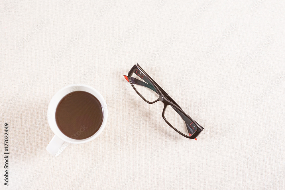 black coffee and eyeglass on fabric background. black coffee and eyeglass on fabric background.