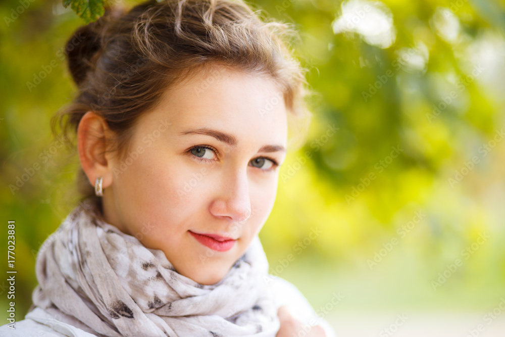Young elegant woman in white coat standing in autumn park. Portrait of stylish girl in fall looking aside with copy space Young elegant woman in white coat standing in autumn park. Portrait of stylish girl in fall looking aside with copy space