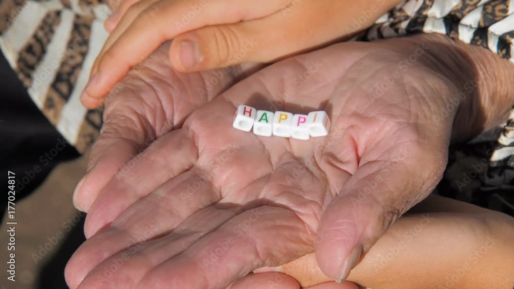 The hands of an elderly woman with a happy word. Children's hands stroke the hands of their grandmother. The hands of an elderly woman with a happy word. Children's hands stroke the hands of their grandmother.