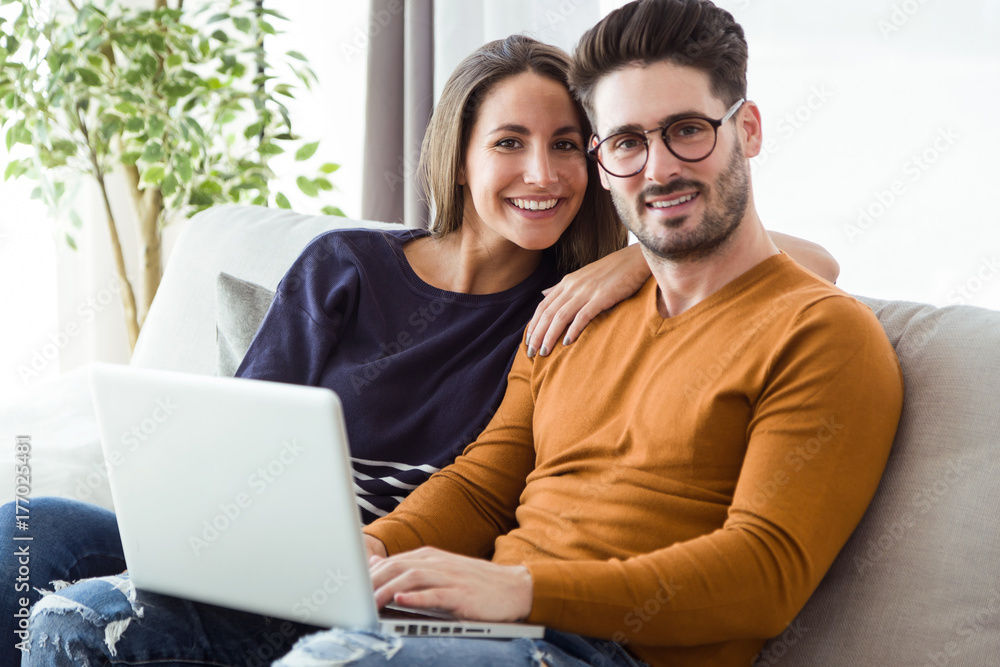 Beautiful young couple using laptop on the sofa at home. Beautiful young couple using laptop on the sofa at home.