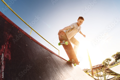 Teen skater hang up over a ramp on a skateboard in a skate park