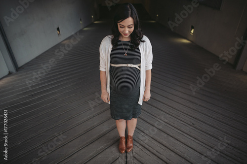 Pretty young pregnant woman standing on patterened road outside photo