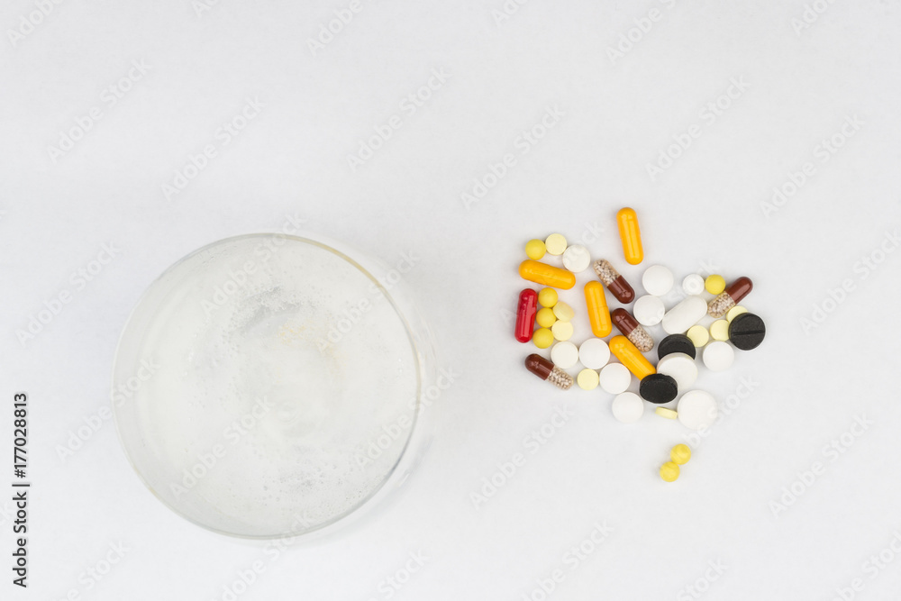 Effervescent tablet in a glass next to a handful of different pills Effervescent tablet in a glass next to a handful of different pills