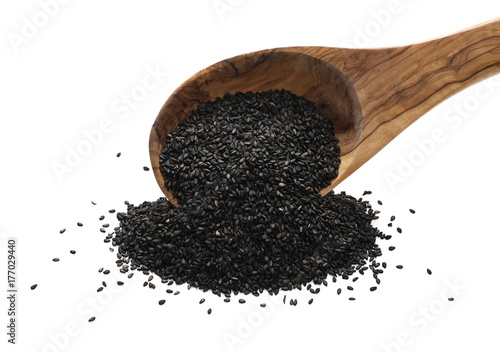 Black organic sesame seeds in wooden spoon isolated on white background