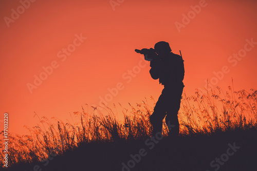 military soldier with weapons at sunset. shot, holding gun, colorful sky. military concept. © kaninstudio