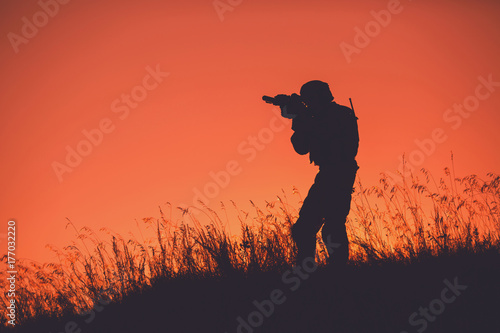 military soldier with weapons at sunset. shot, holding gun, colorful sky. military concept.